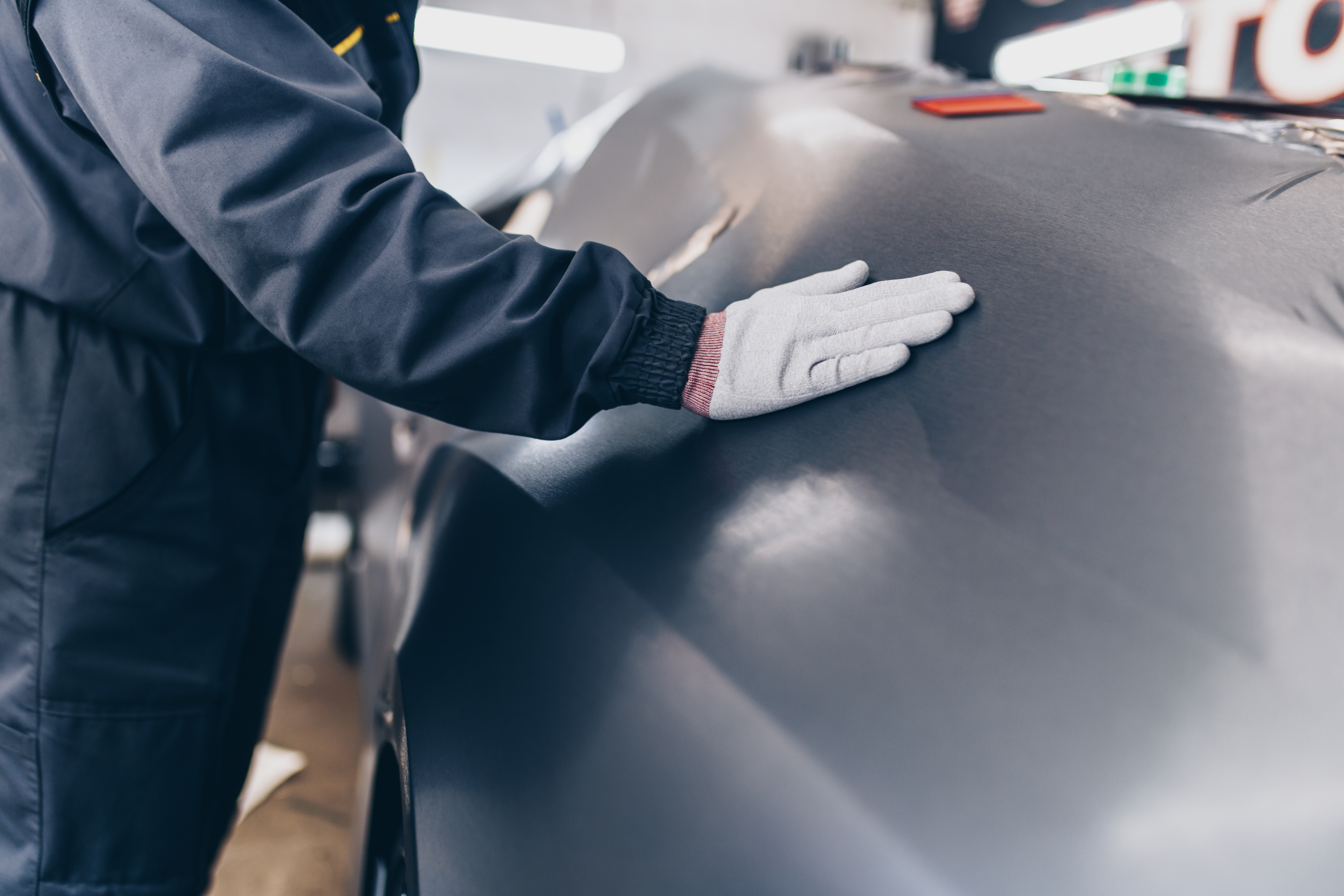 Careful hands applying wrap film to a vehicle